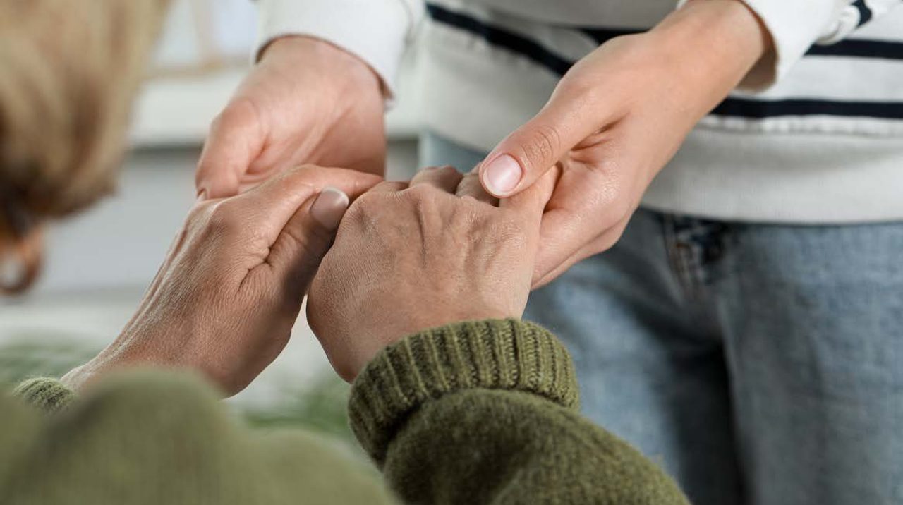 A carer holding a resident’s hand